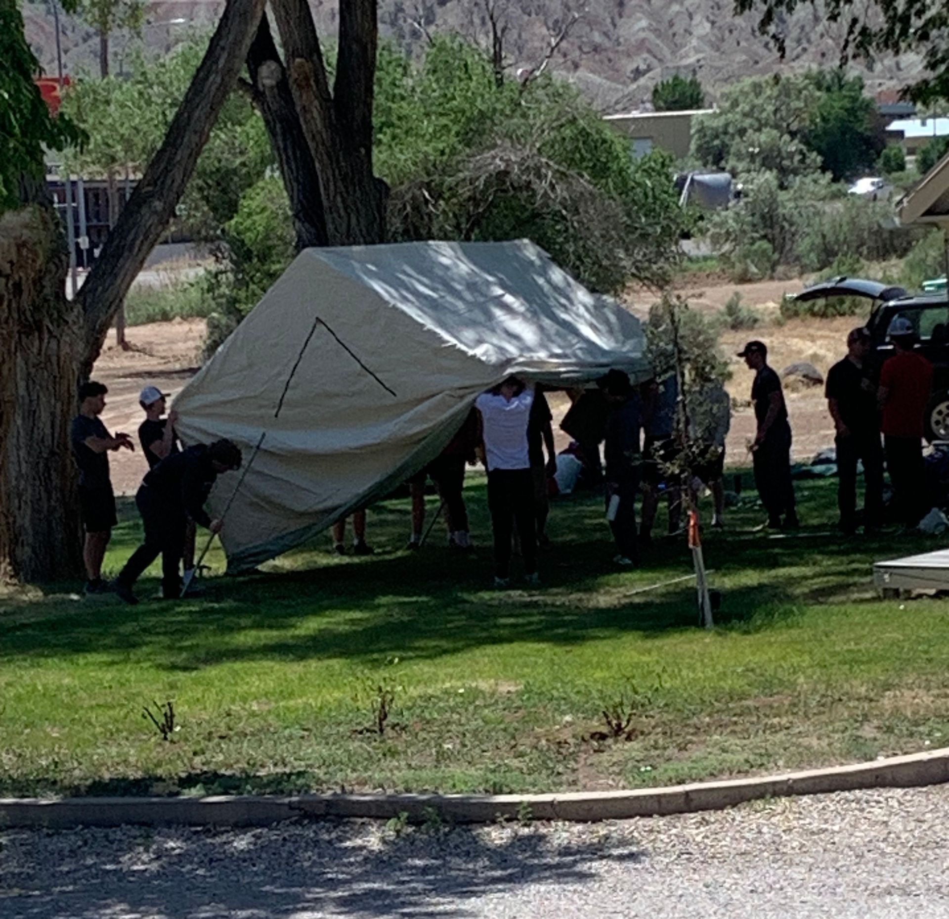 A group of people standing around a tent in a park