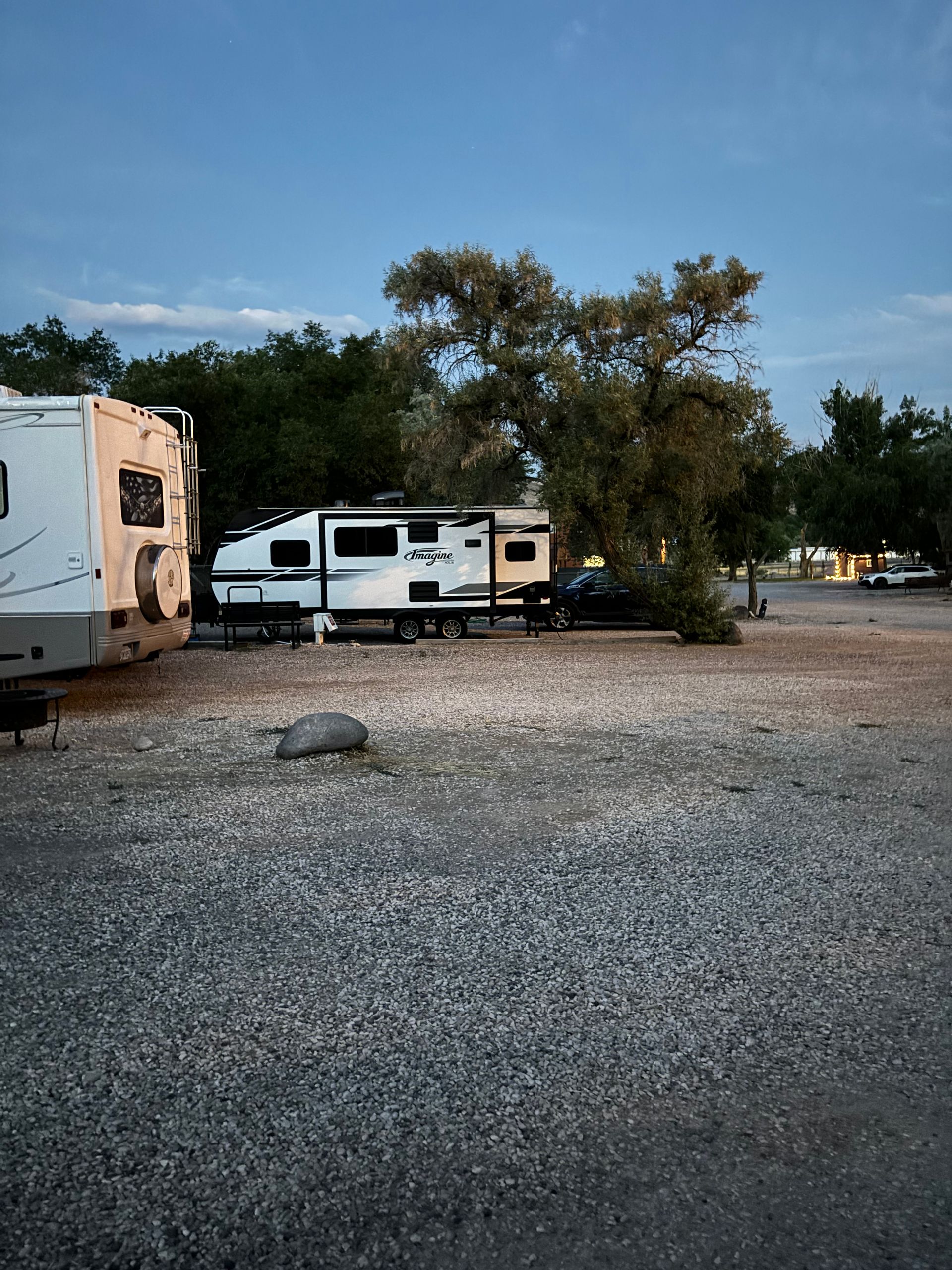 A couple of rvs are parked in a gravel lot