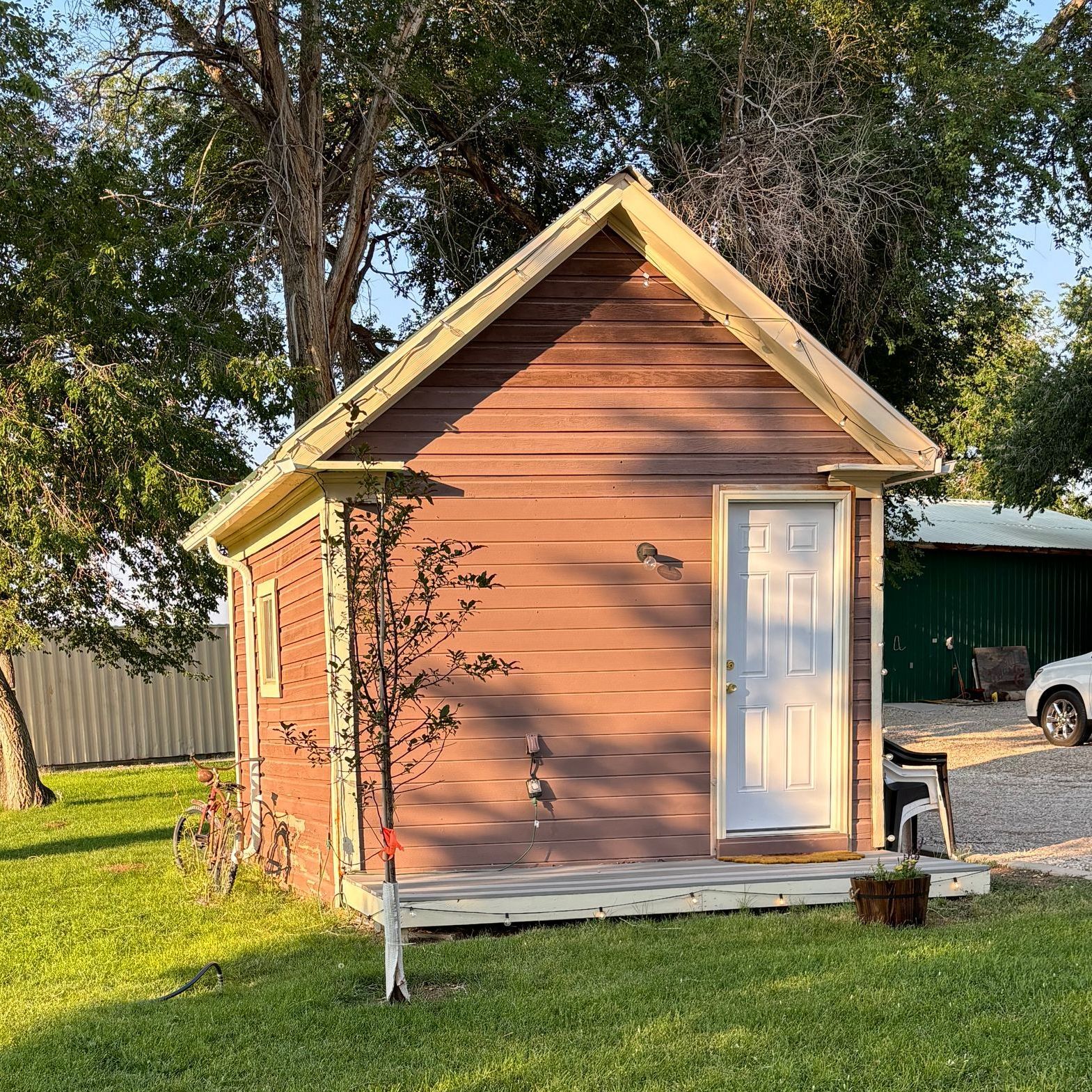 A small house is sitting in the middle of a lush green field.