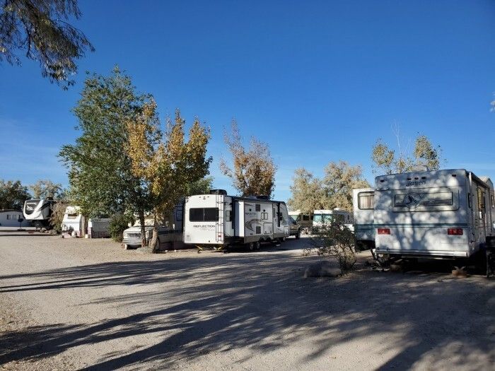 A row of rvs parked in a dirt lot.