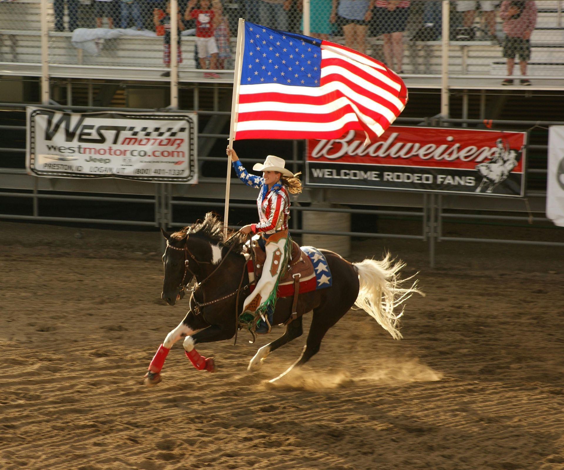 A woman riding a horse holding an american flag