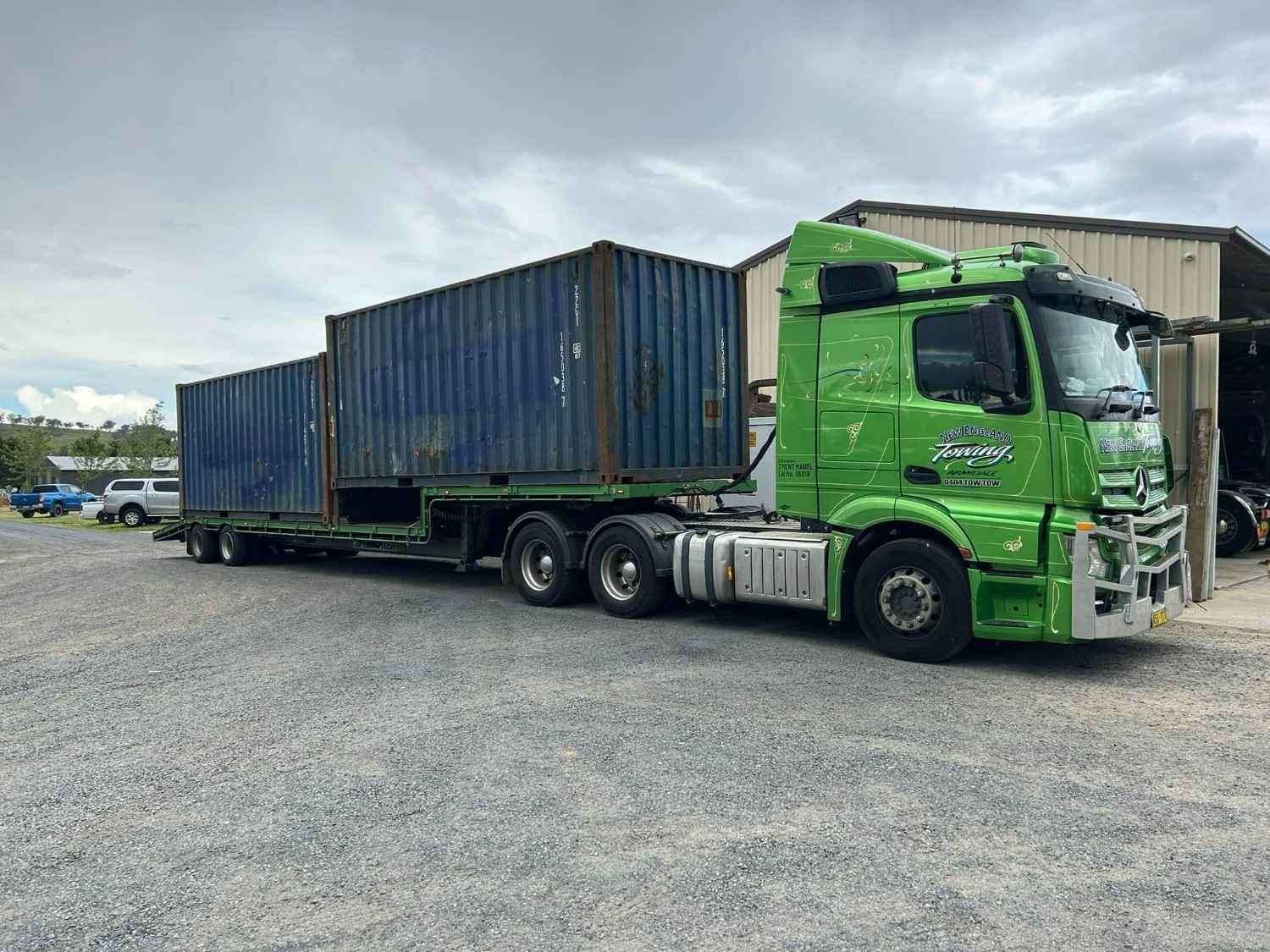 Green Semi-Truck Hauling Two Blue Shipping Containers on A Gravel Lot — New England Towing in Warialda, NSW
