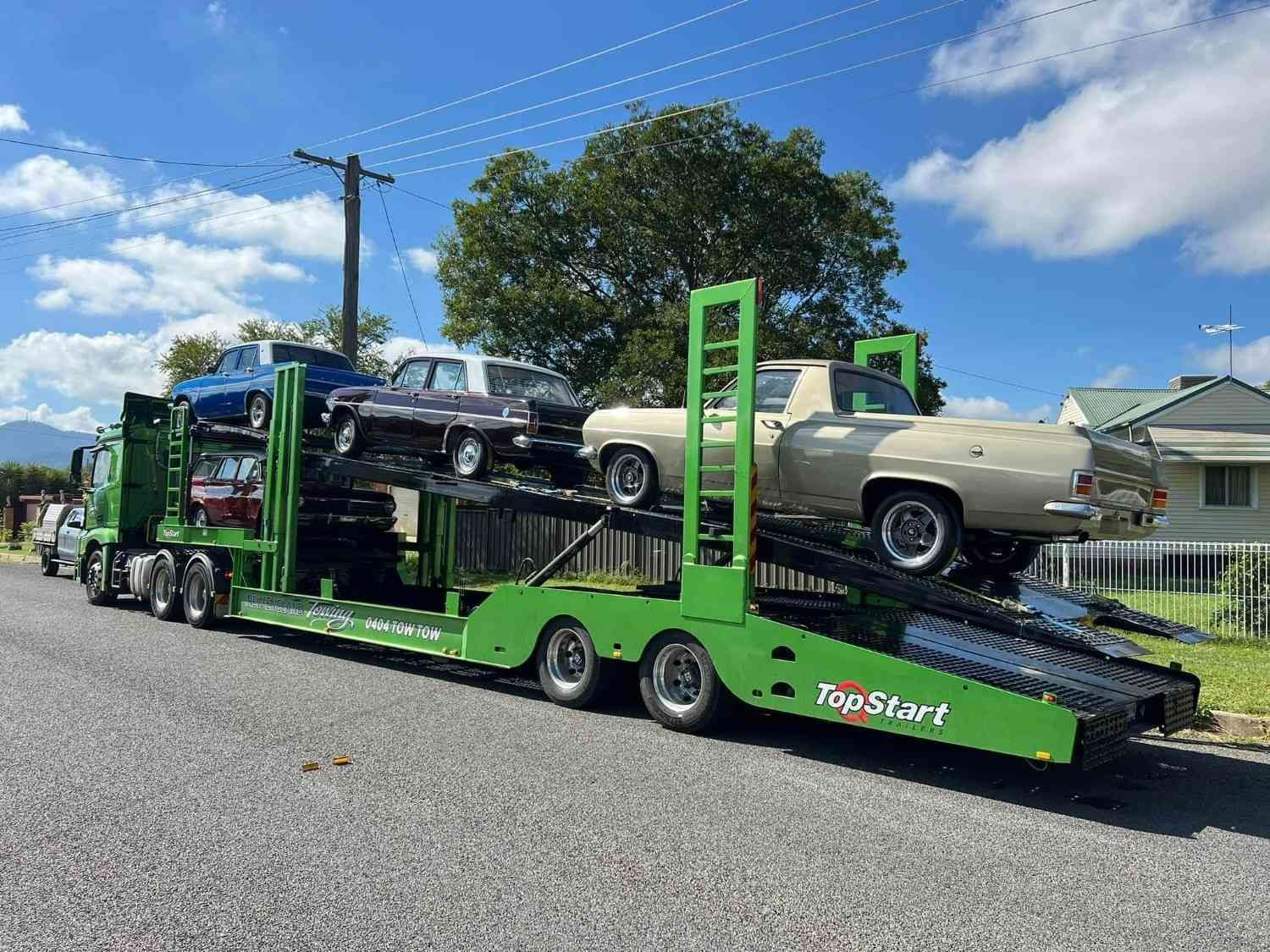 A Green Car Hauler Truck Carrying Several Vintage Cars — New England Towing in Guyra, NSW