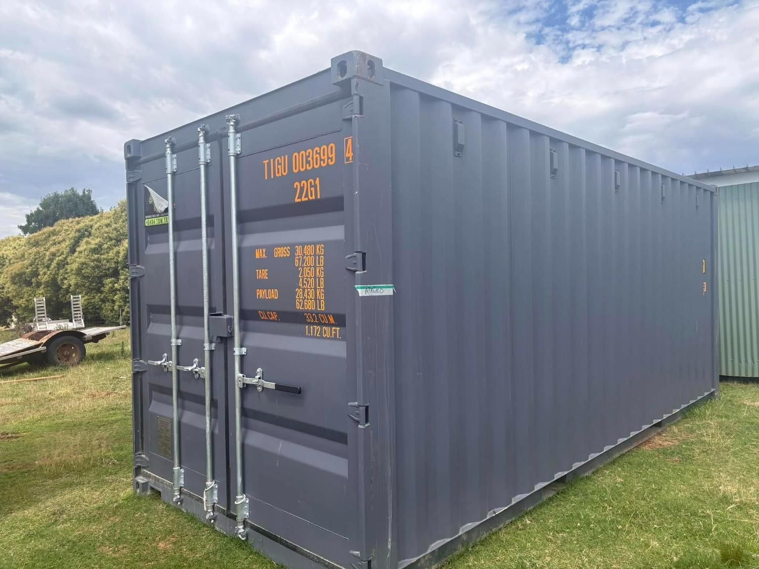 A Dark Gray Shipping Container Sits on Green Grass — New England Towing in Warialda, NSW