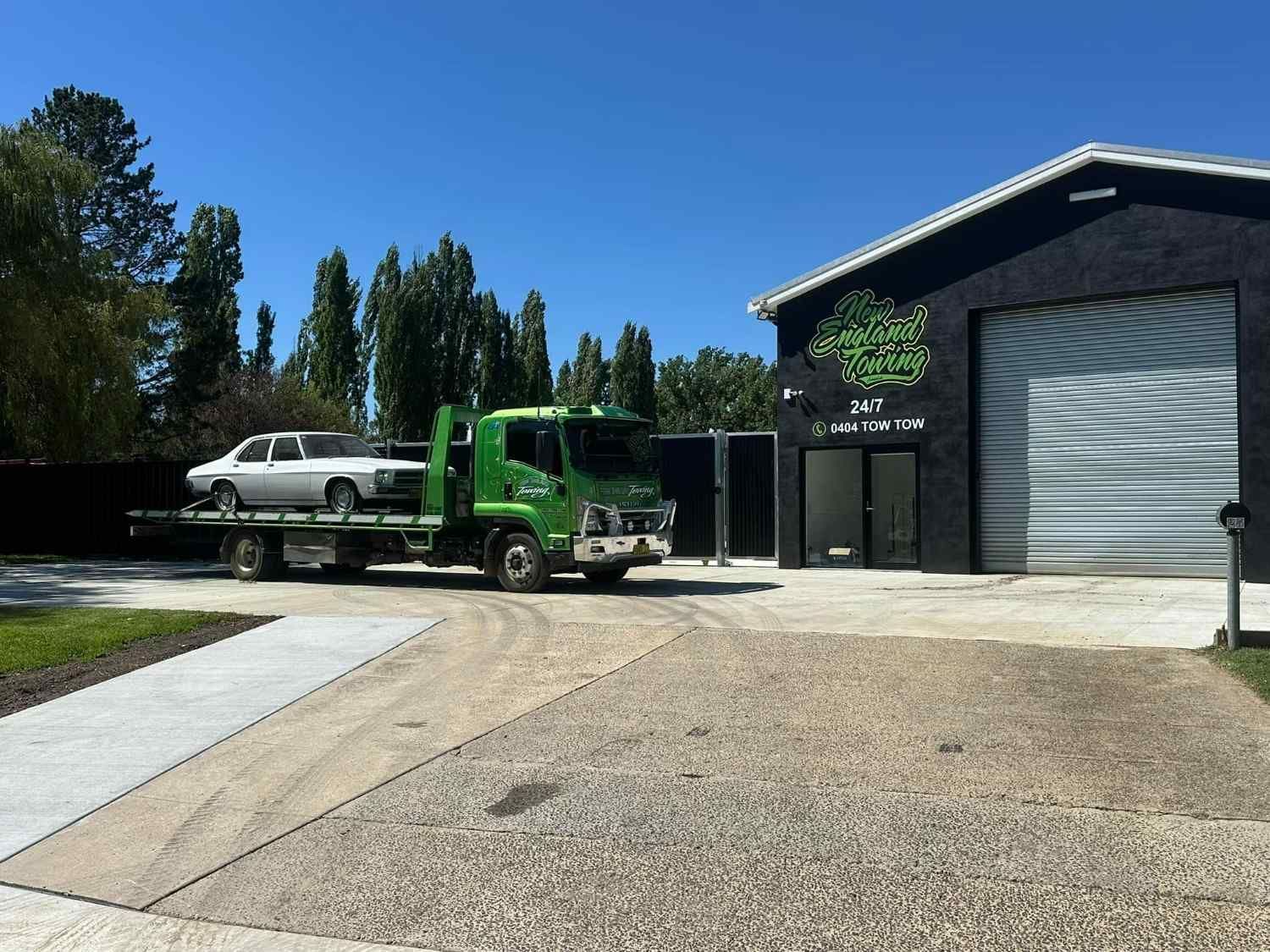 A Green Tow Truck with A White Car on Its Flatbed — New England Towing in Walcha, NSW