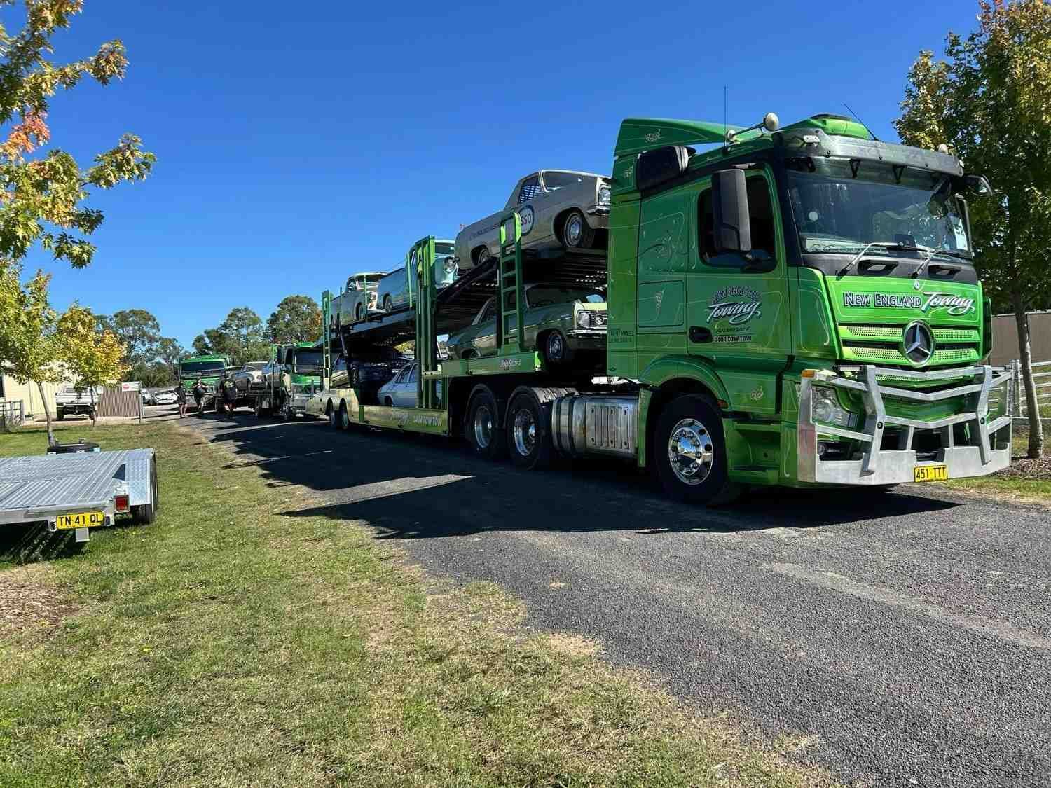 A Green Car Transporter Truck Loaded with Vehicles Parked on A Gravel Road — New England Towing in Ebor, NSW