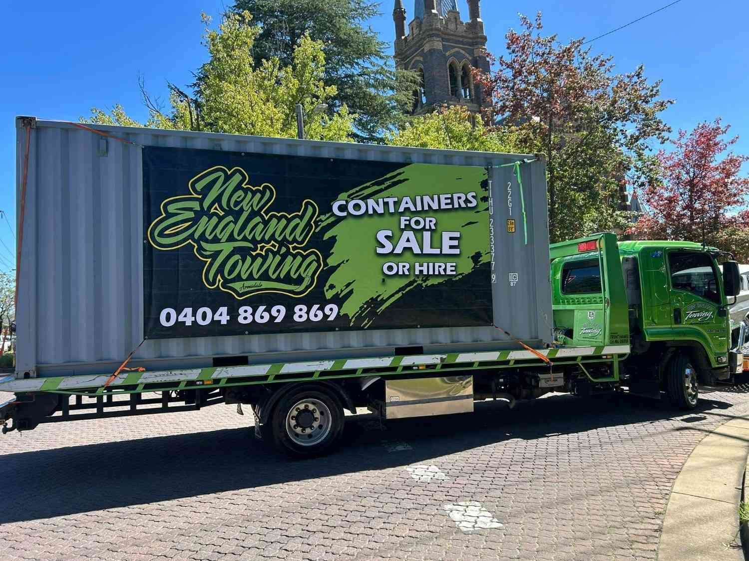 A Green Truck Hauling a Gray Shipping Container with New England Towing — New England Towing in Walcha, NSW