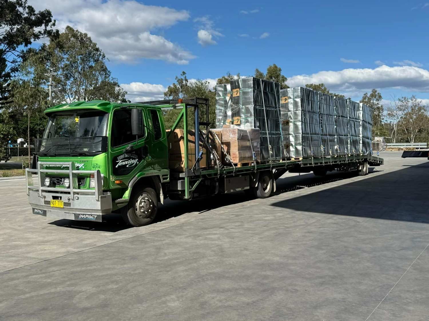 Green Semi-Truck Loaded with Stacks of Metal Containers — New England Towing in Walcha, NSW