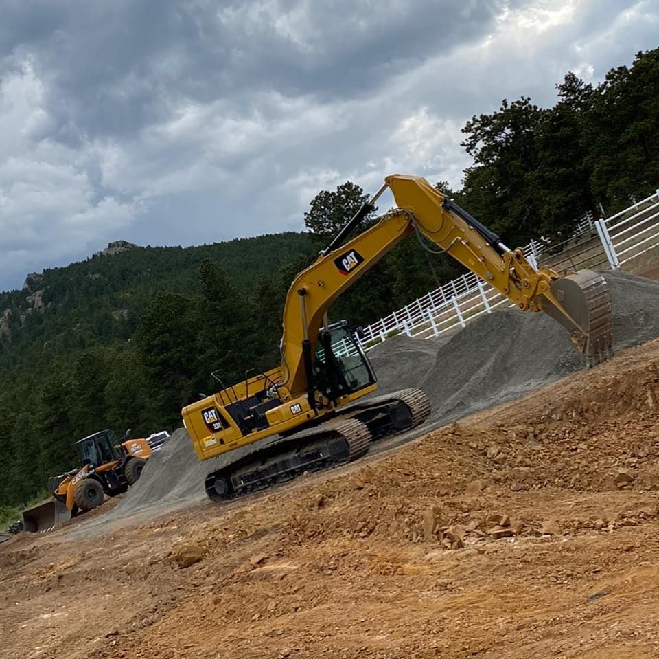 A yellow cat excavator is digging in a dirt field