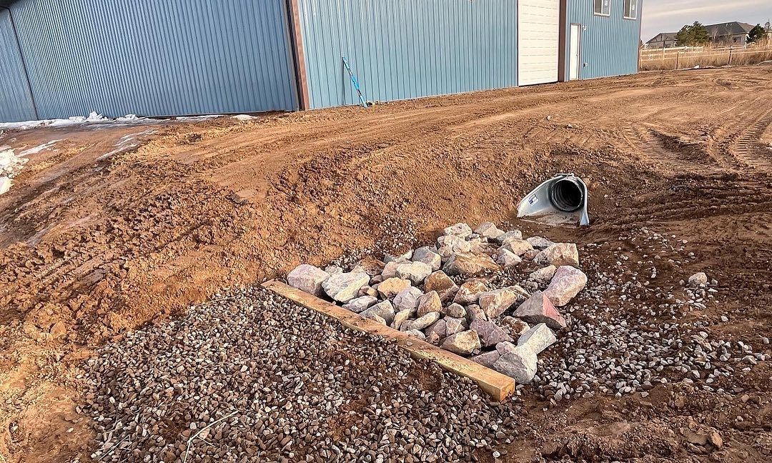 A pile of rocks is sitting in the dirt in front of a building.