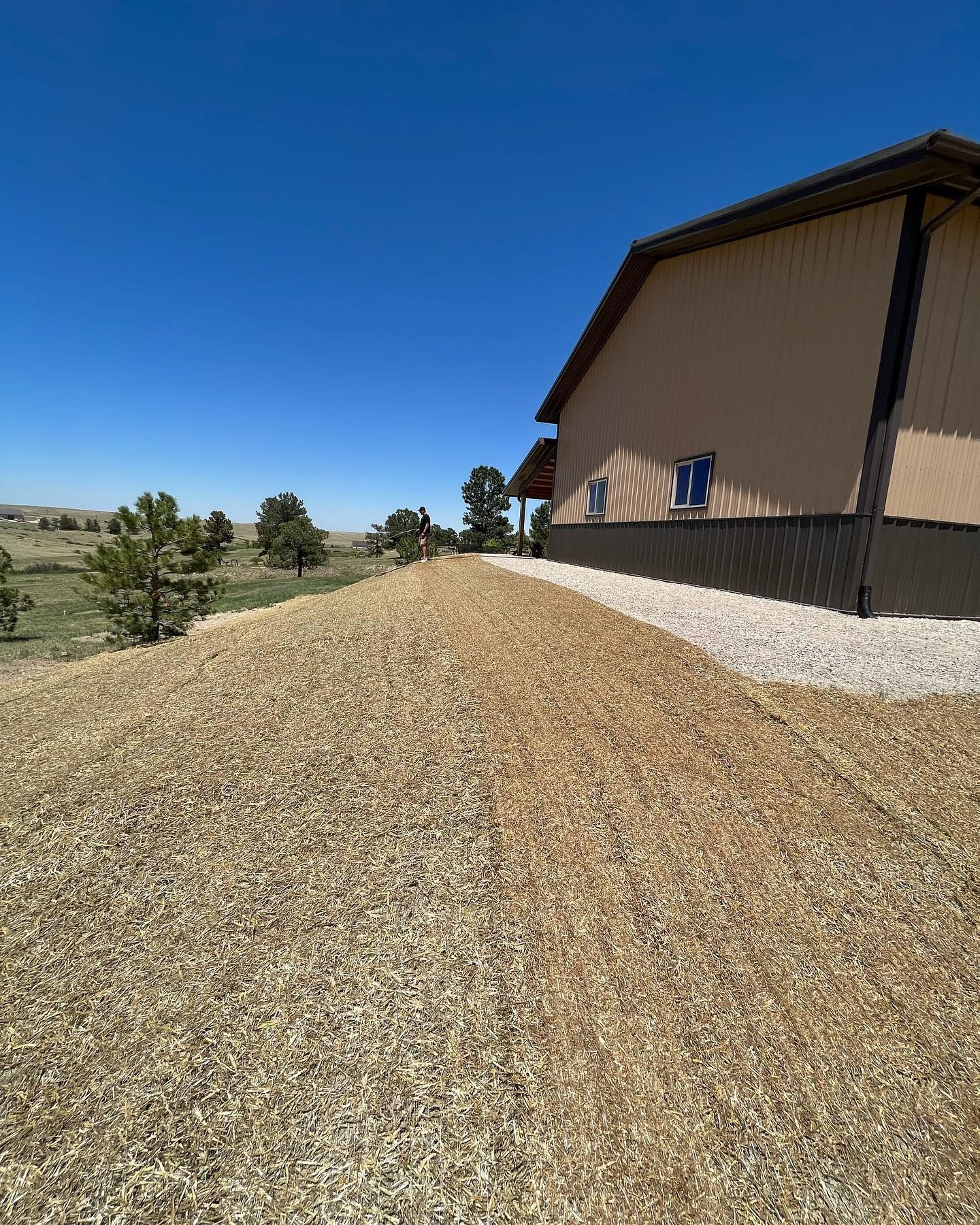 A house is sitting on top of a dirt hill next to a gravel road.