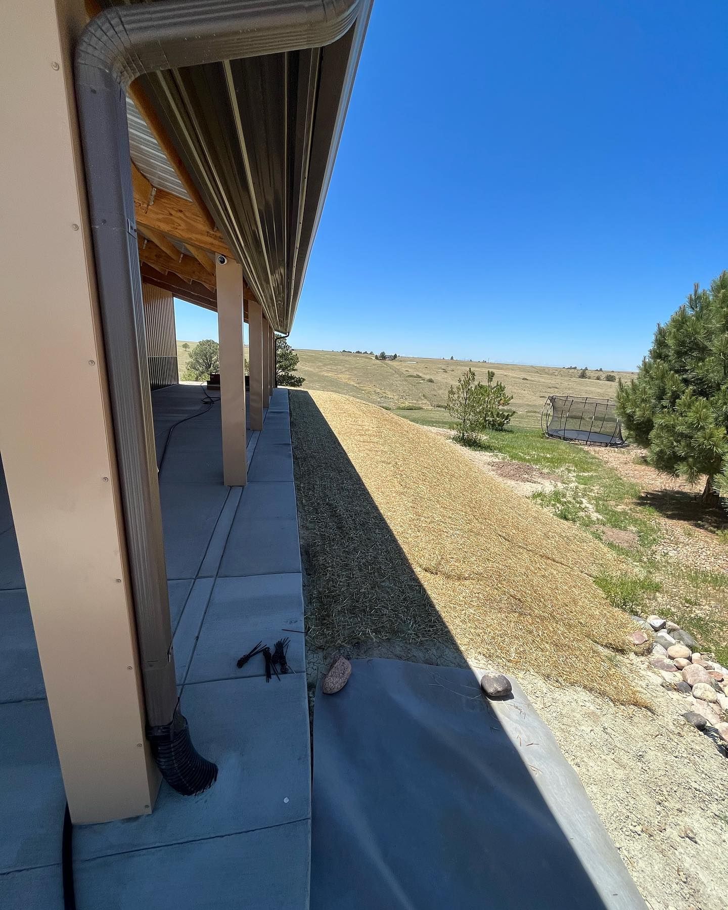 A house with a gutter on the side of it and a view of a field.