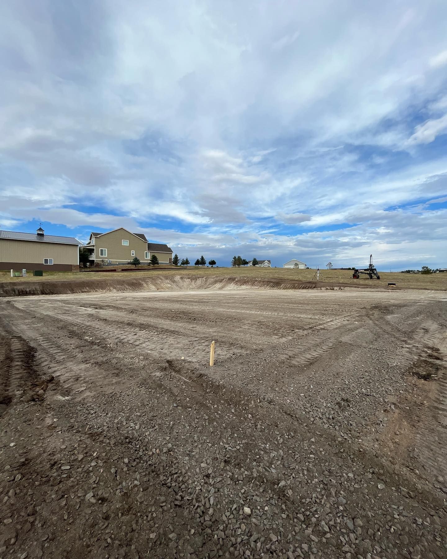 A large dirt field with a house in the background.