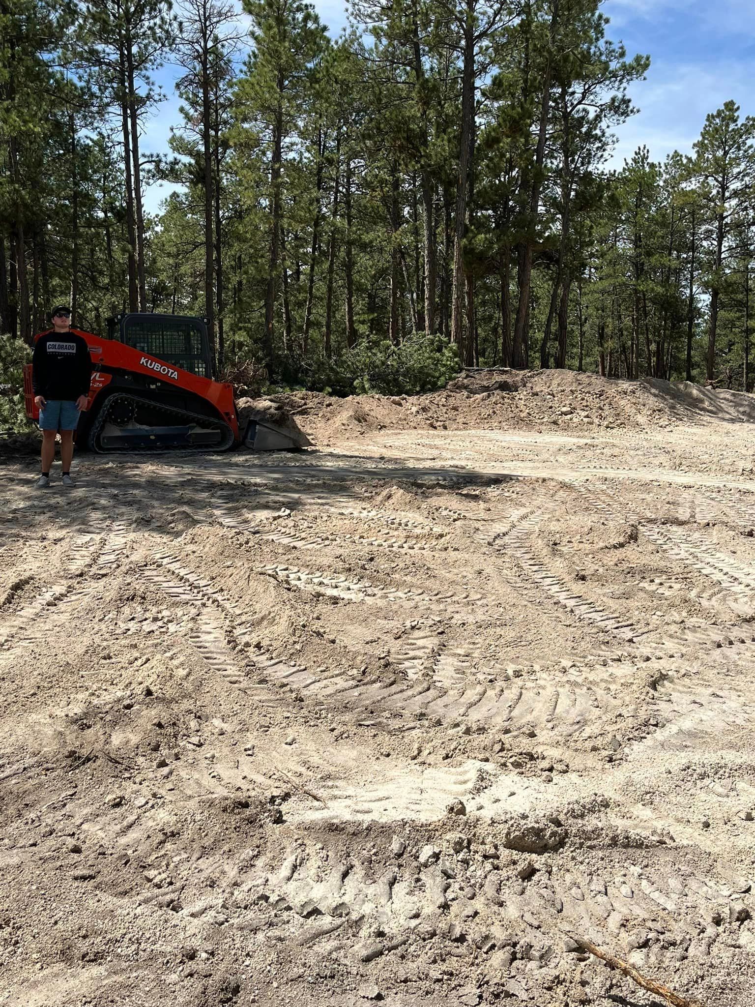 A man is standing next to a bulldozer in a dirt field.