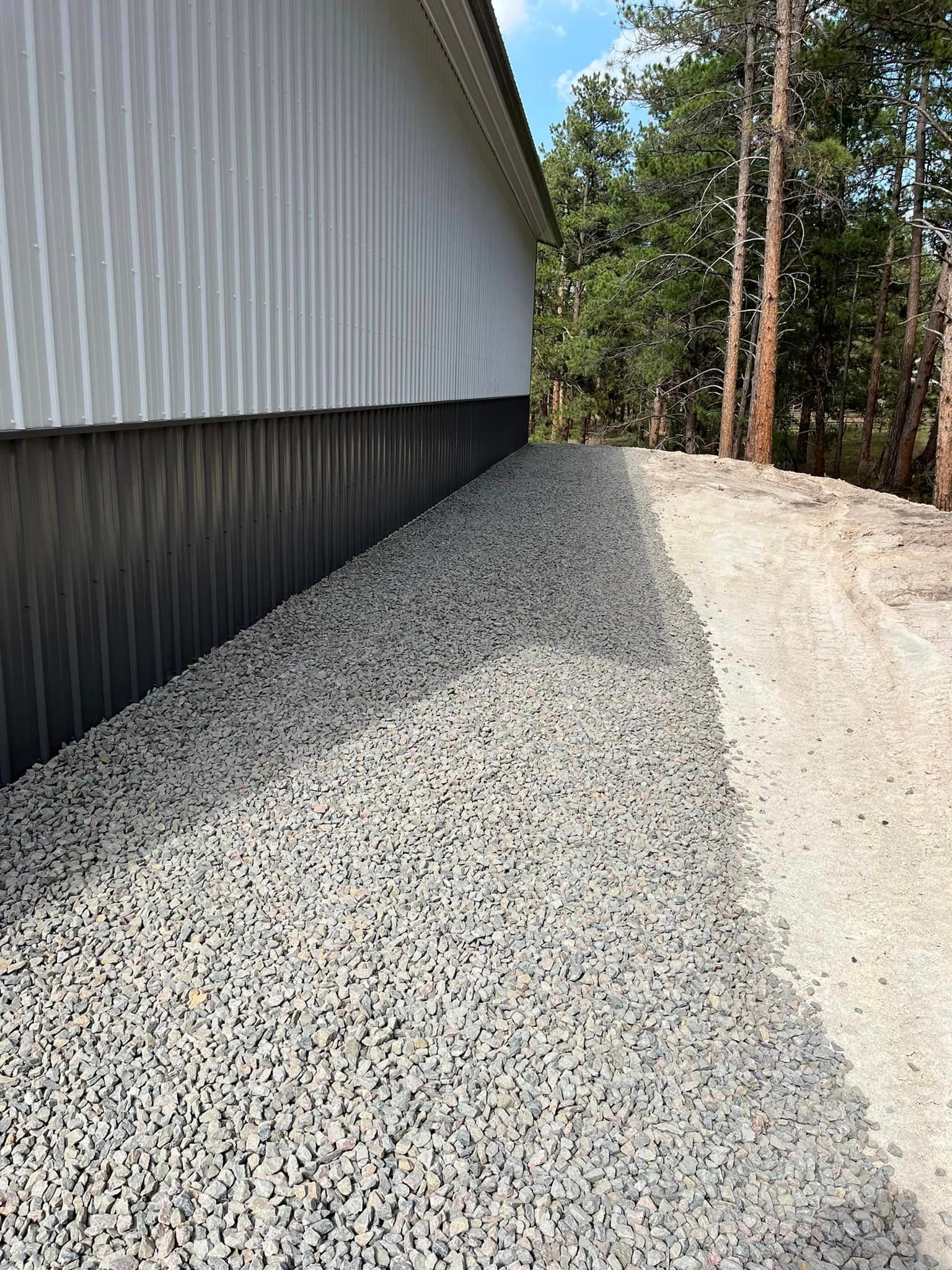 A gravel path leading to a building with trees in the background.