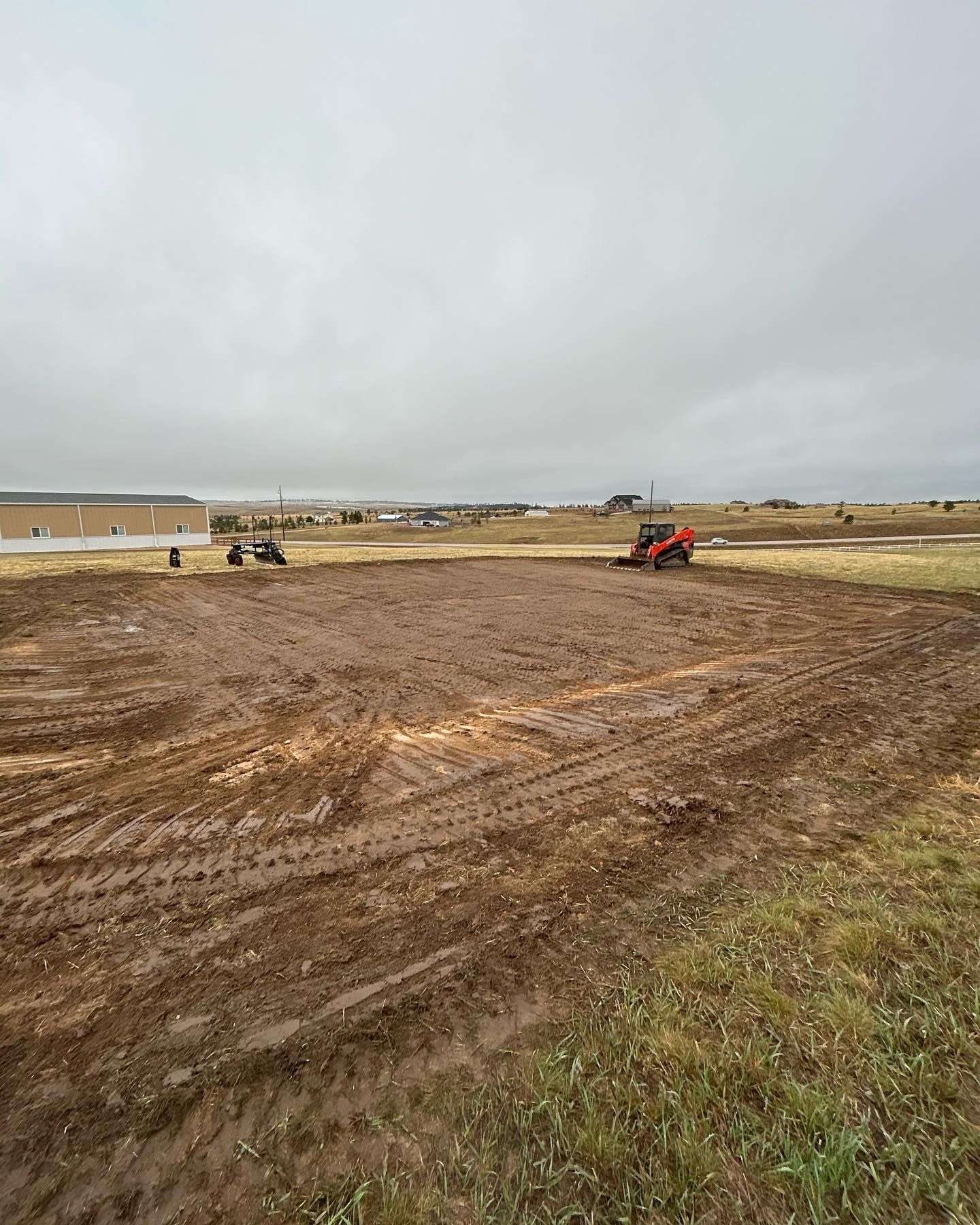 A tractor is plowing a muddy field on a cloudy day.