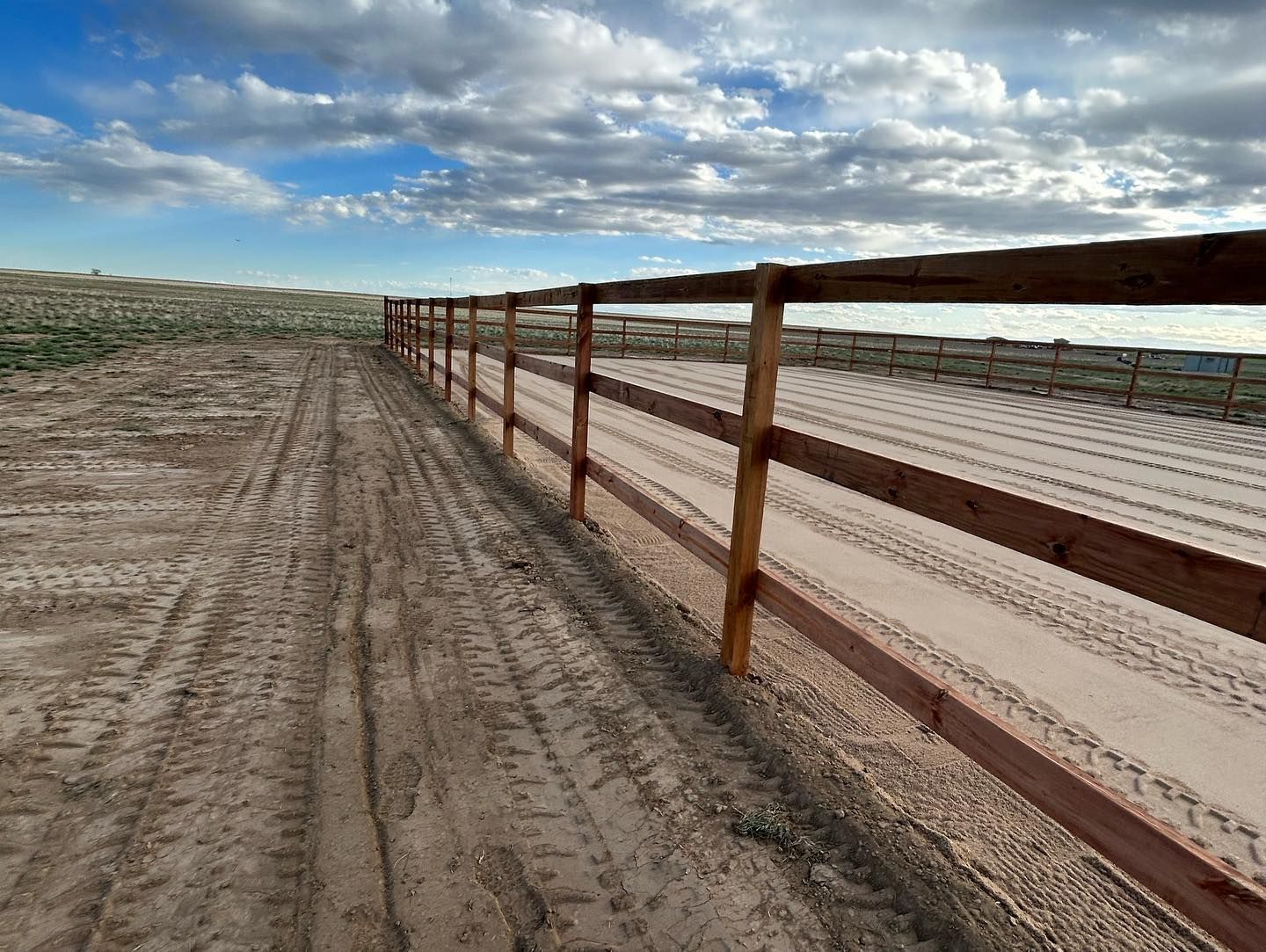 A wooden fence along a dirt road in the desert