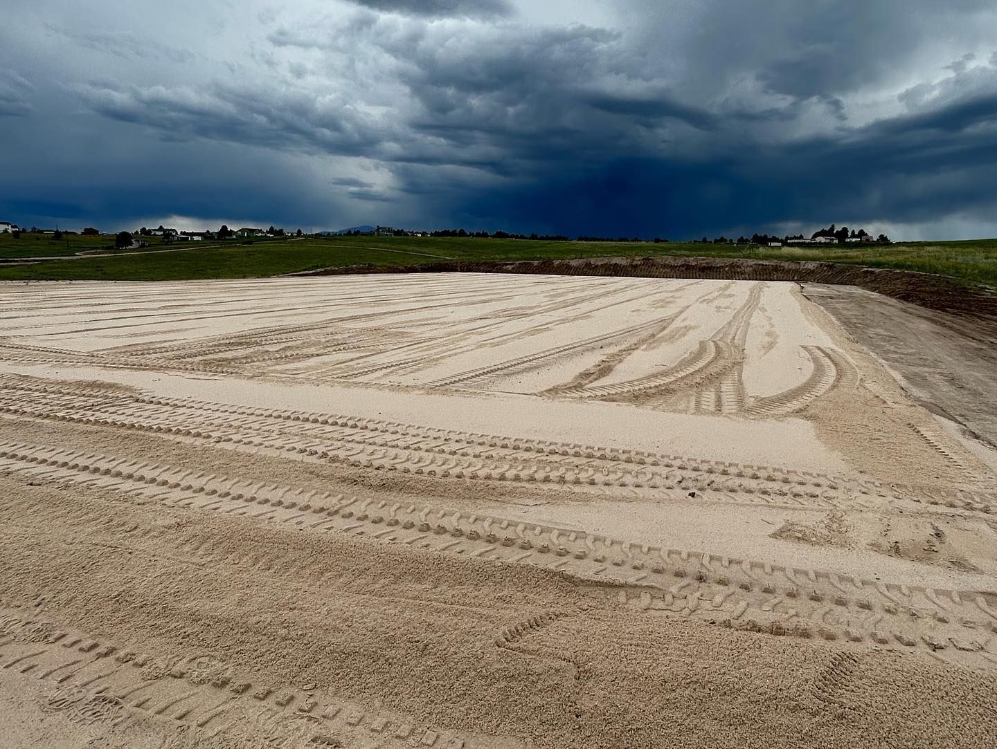 A dirt field with a cloudy sky in the background.