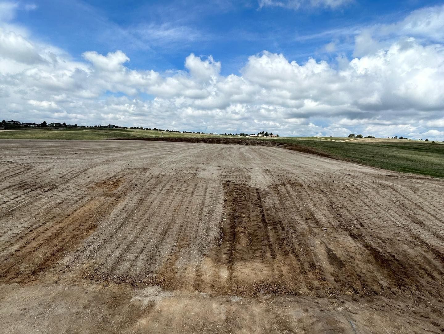 A dirt field with a blue sky and clouds in the background