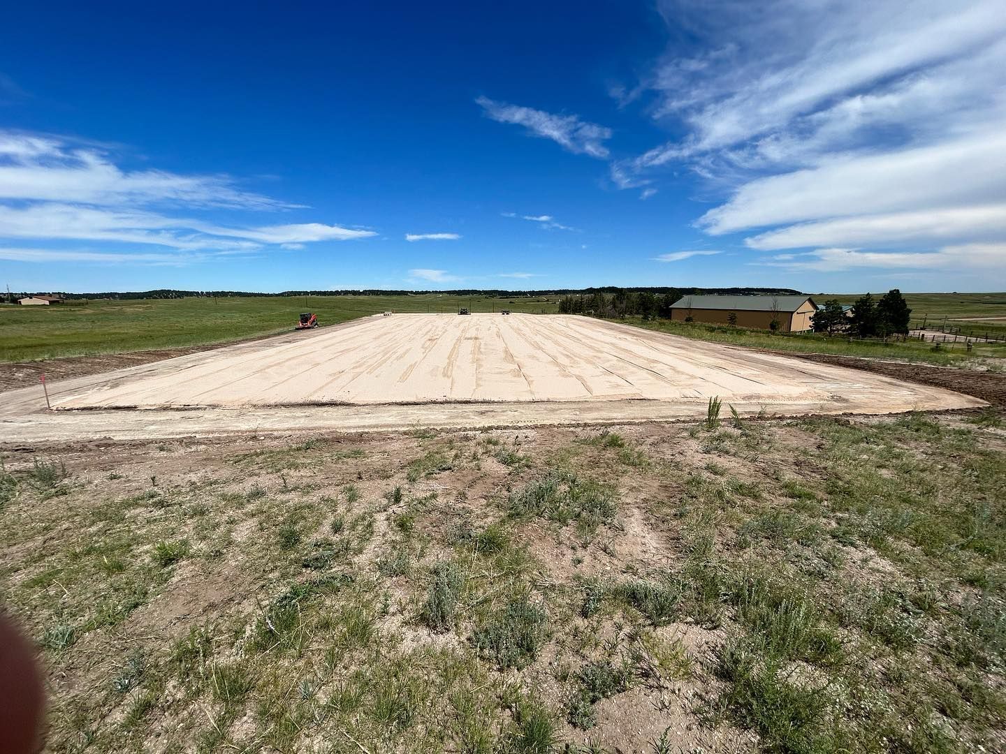 A large dirt field with a house in the background