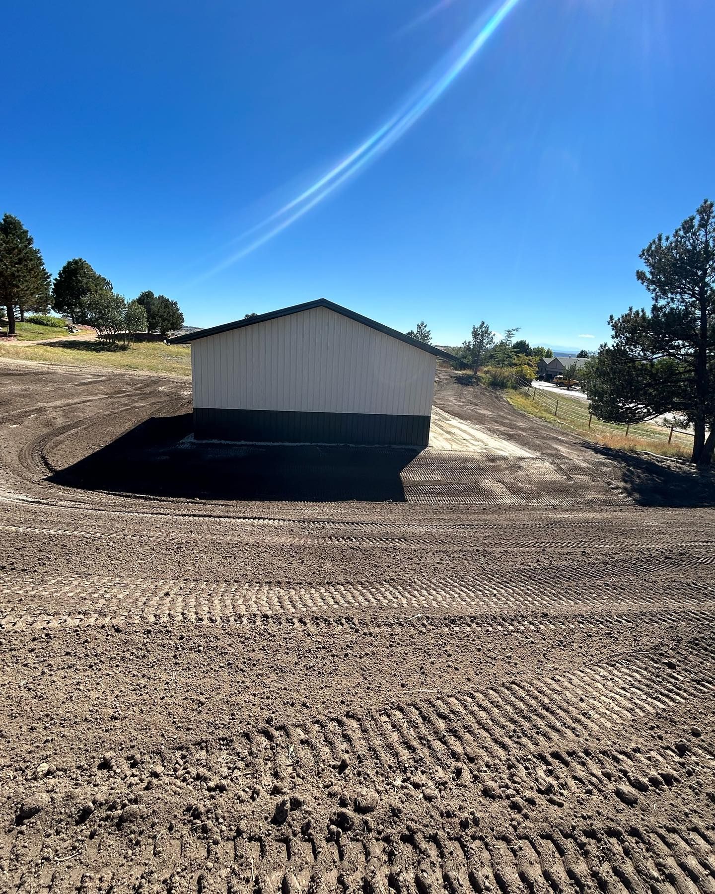 A small white building is sitting in the middle of a dirt field.