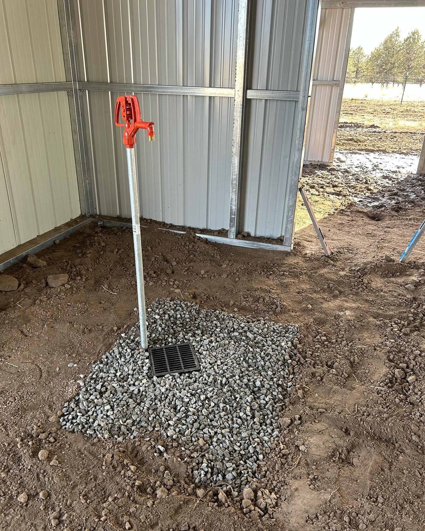 A faucet is sitting on top of a pile of gravel in a shed.
