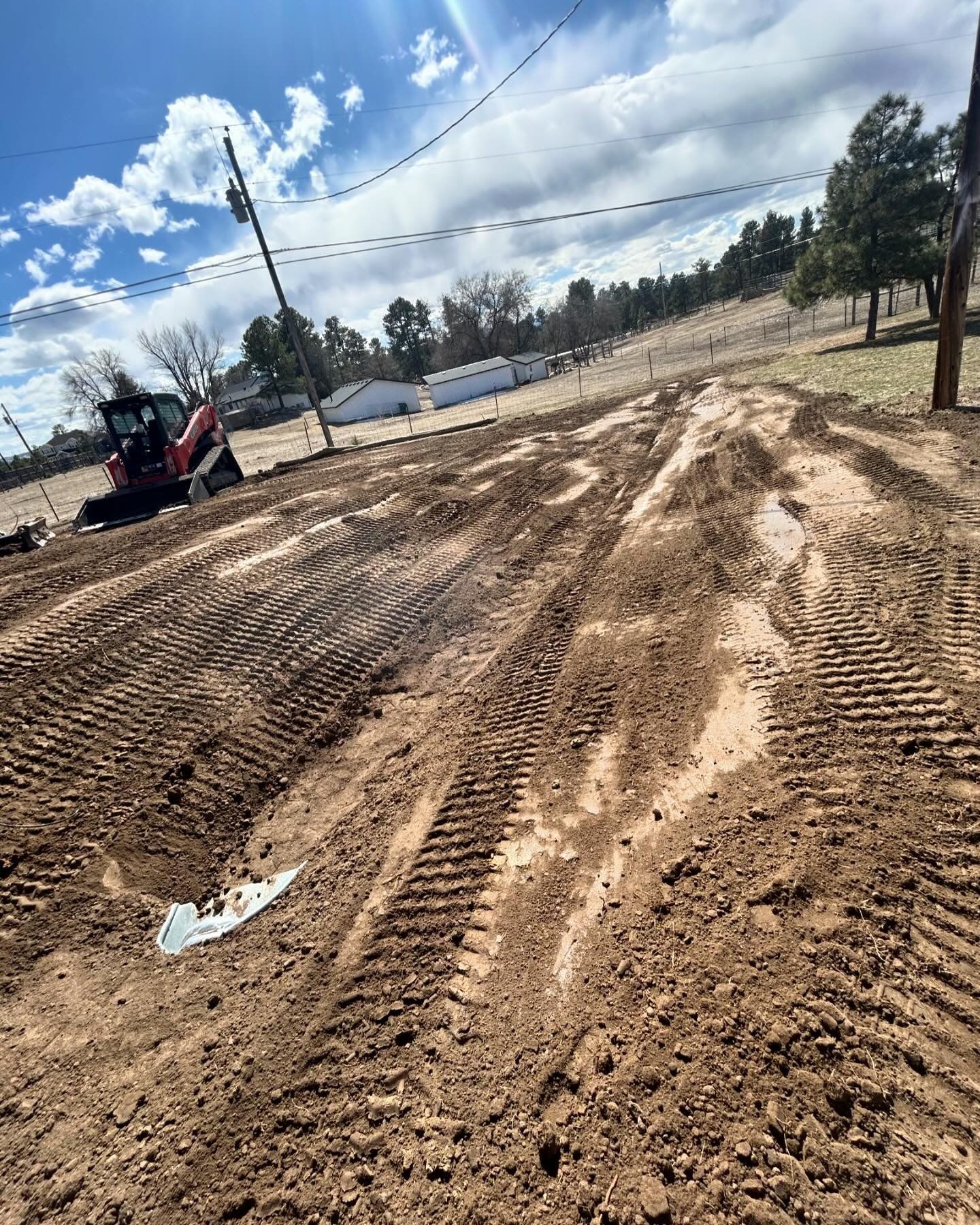 A tractor is driving down a dirt road.