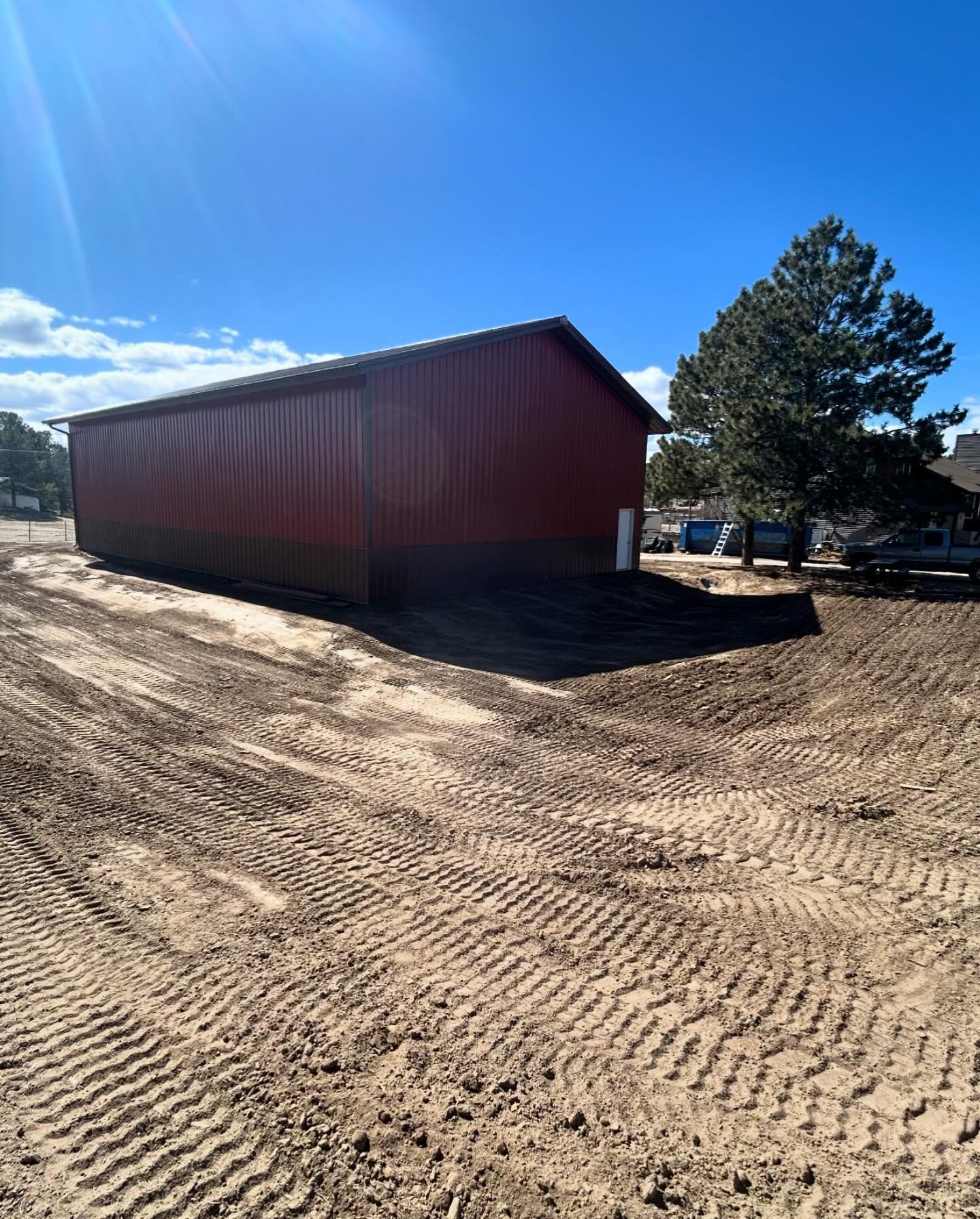 A red barn is sitting in the middle of a dirt field.