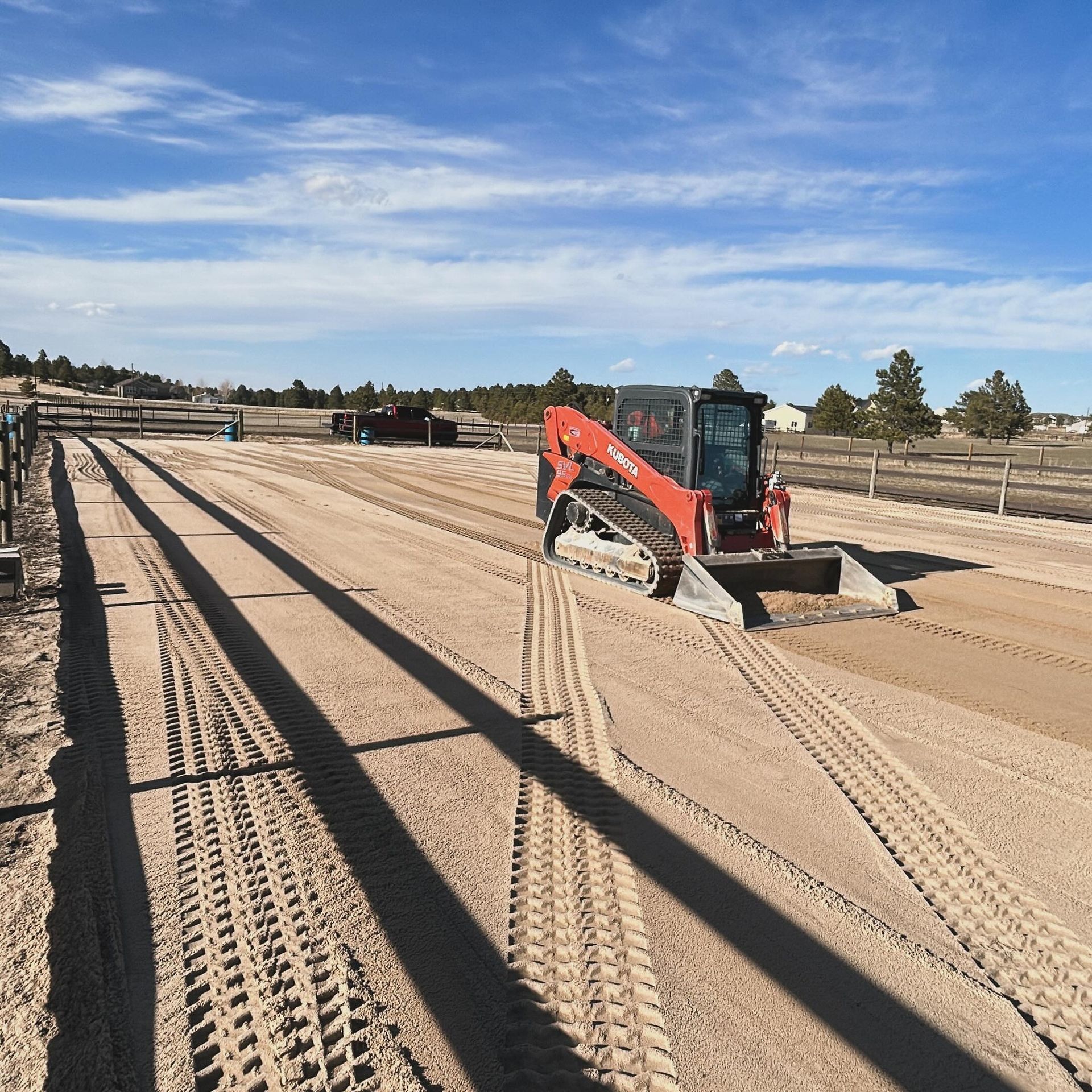 A red bulldozer is working on a dirt road