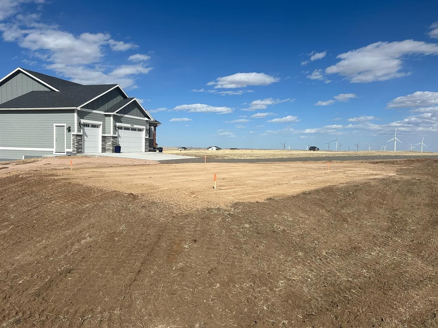 A house is sitting in the middle of a dirt field.