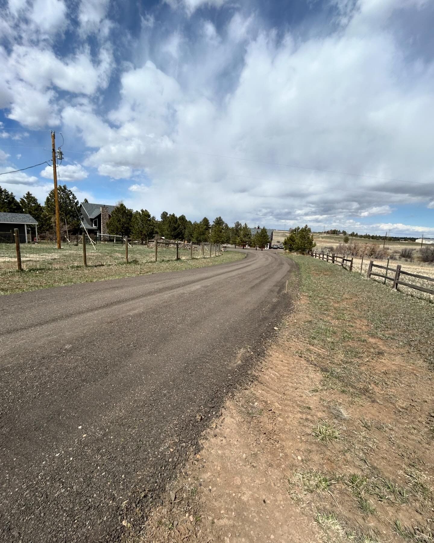 A dirt road with a wooden fence on the side of it