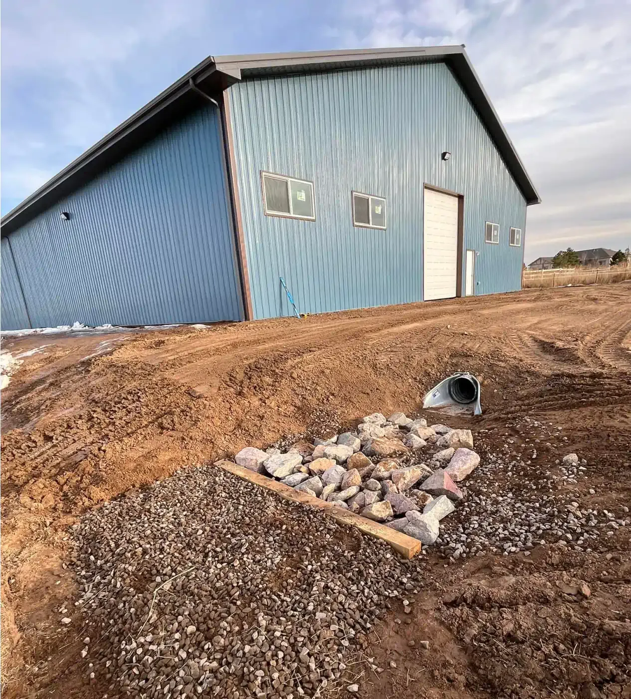A blue building is sitting on top of a dirt hill.