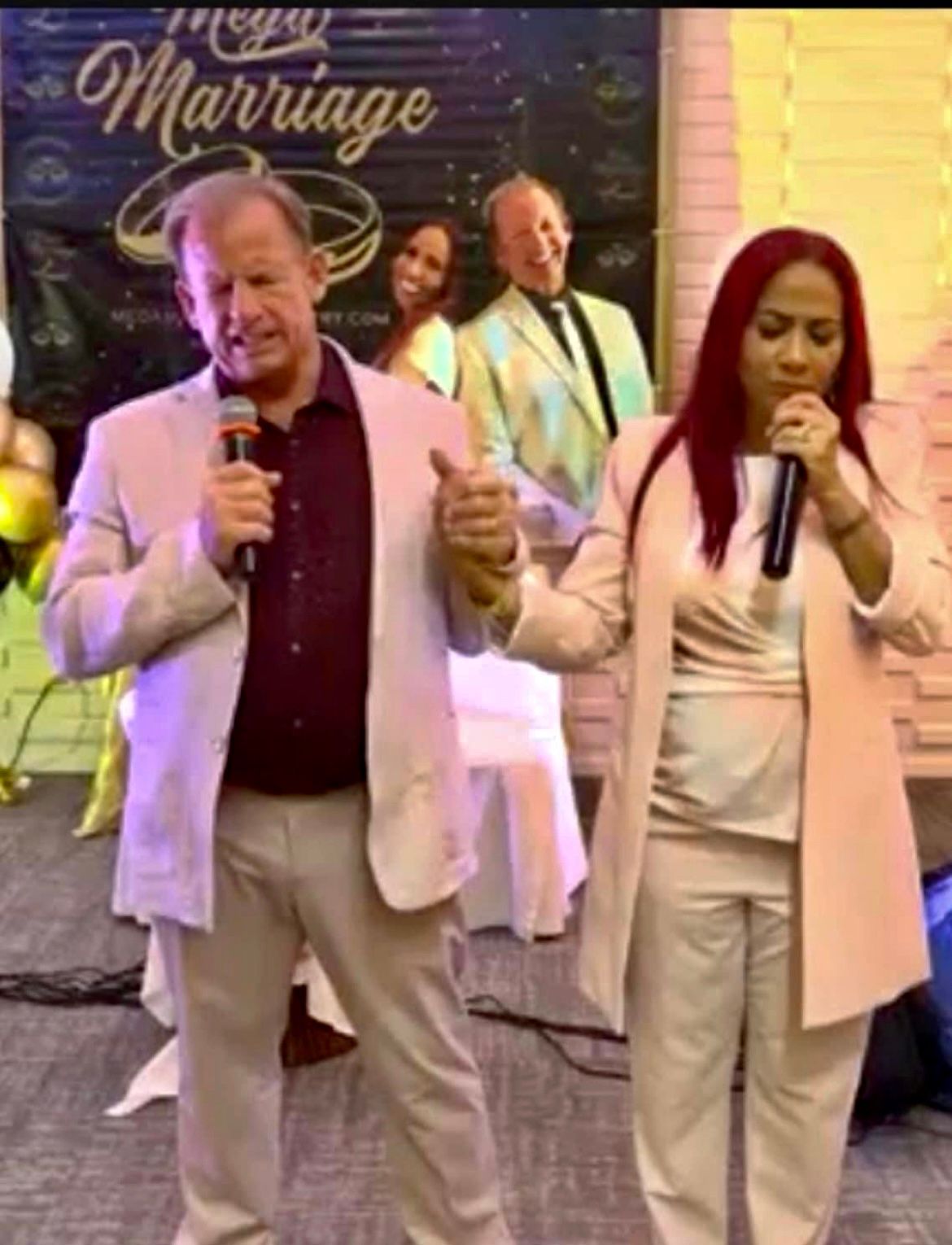 A man is holding a microphone next to a woman who is singing into a microphone.