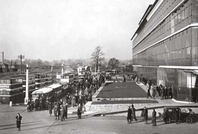 A black and white photo of people walking in front of a large building.