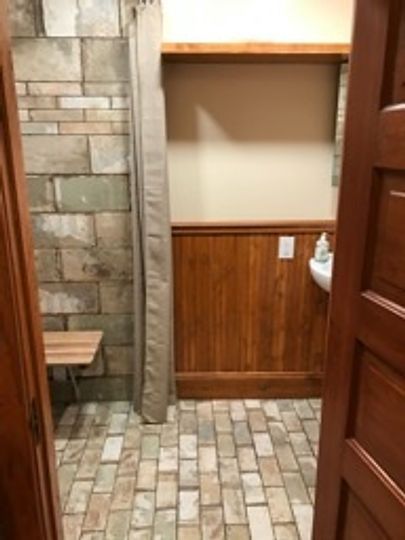 A bathroom with a brick floor and wood paneling