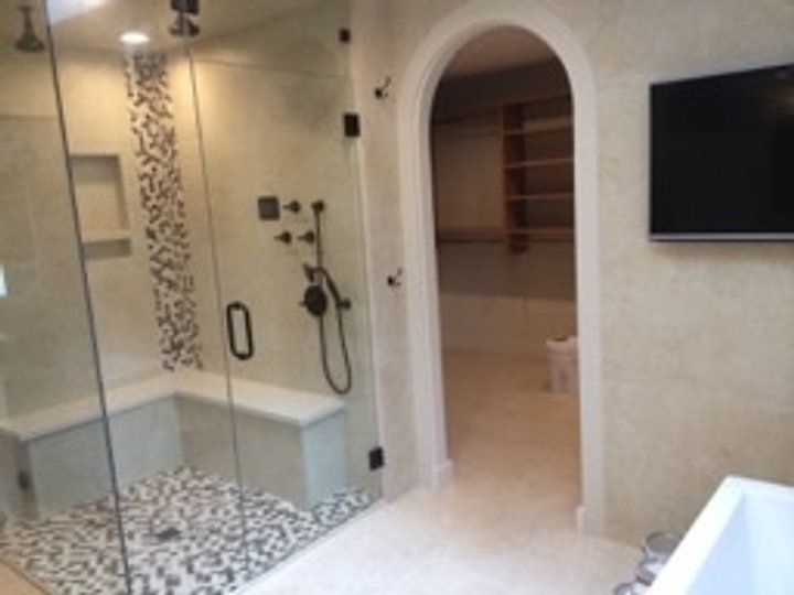 A bathroom with a walk in shower and a flat screen tv