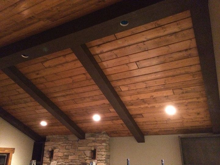 A wooden ceiling with a stone fireplace in the background
