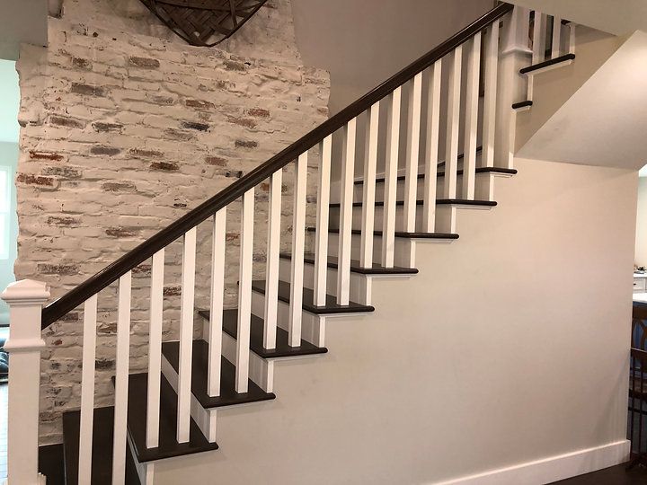 A staircase with white railings and a brick wall behind it