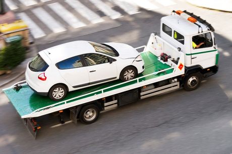 Car loaded on truck, arm tightening tow strap. 