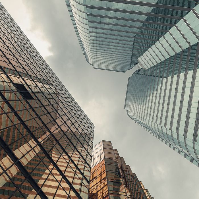 Looking up at a group of tall buildings with a cloudy sky in the background.