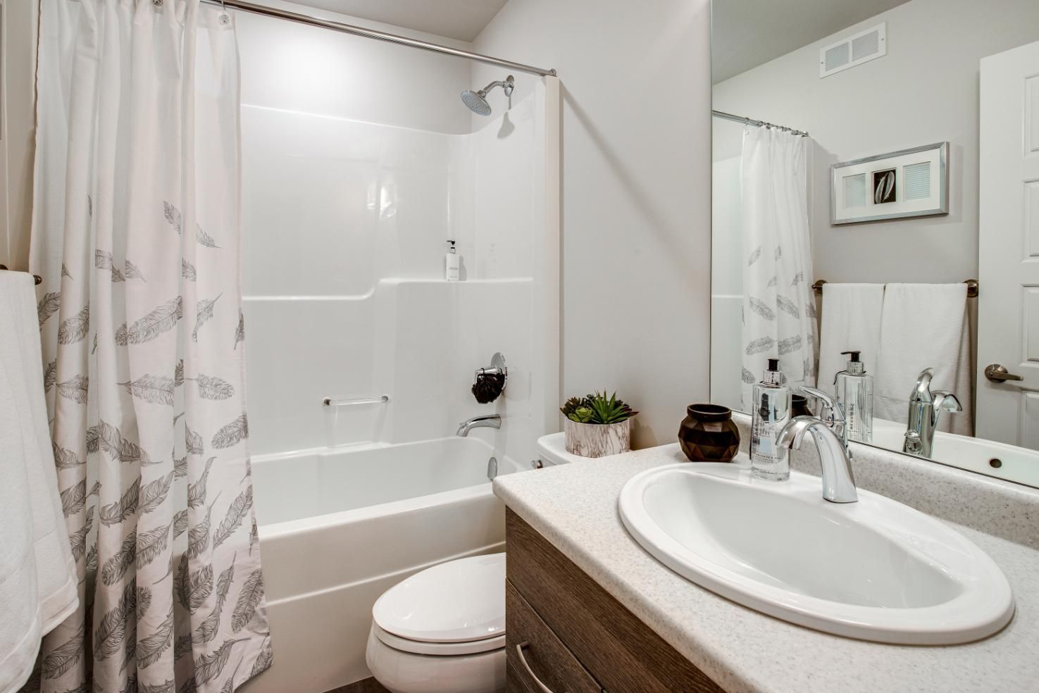 Bathroom with white tub/shower, sink, and toilet. 