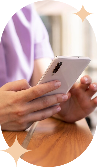 Una persona está sentada en una mesa usando un teléfono celular.