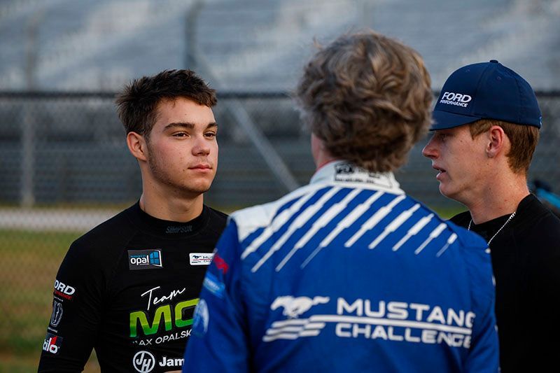 Max Opalski in a black Team MOR shirt is talking to two race drivers.