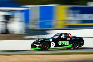 Max Opalski is sitting on the hood of a green race car.