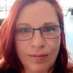 A close up of a woman wearing glasses and red hair.