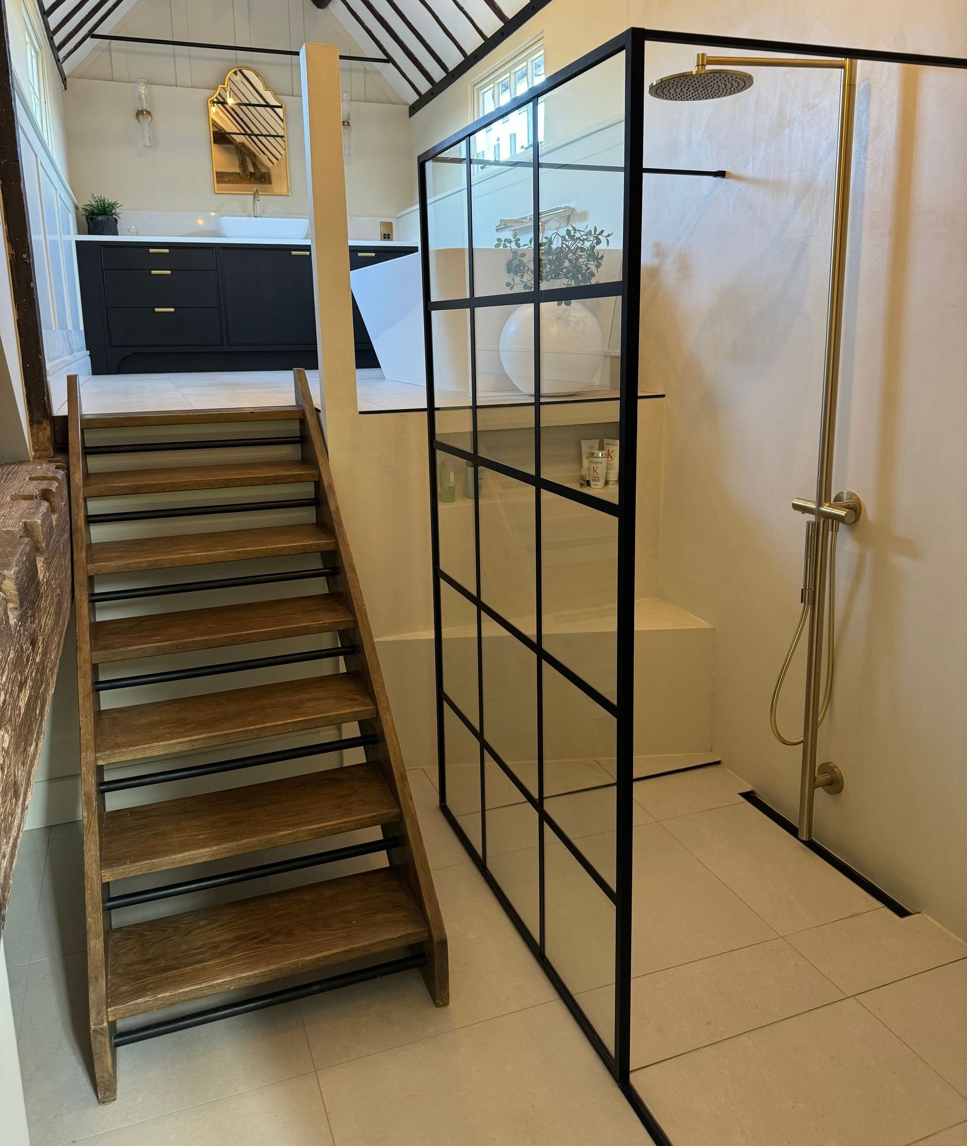 Wooden staircase beside a modern shower with black framed glass, and black cabinets.