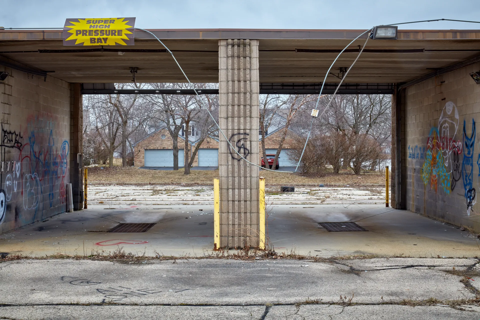 Carwash Across the Street. Abandoned car wash within a residential neighborhood, now home to teenagers and drunkards. Streamwood, Illinois 2023 - Robert Swiderski
