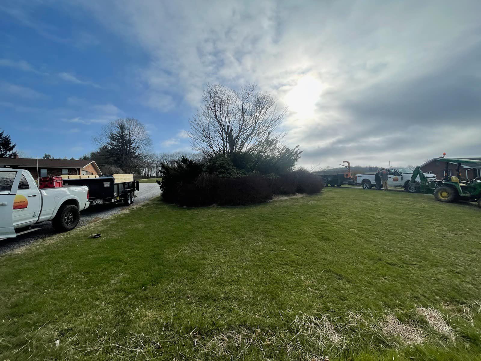 A White Truck Is Being Towed By A Green Tractor In A Grassy Field - Roanoke, VA - Duncan Design & Landscaping LLC