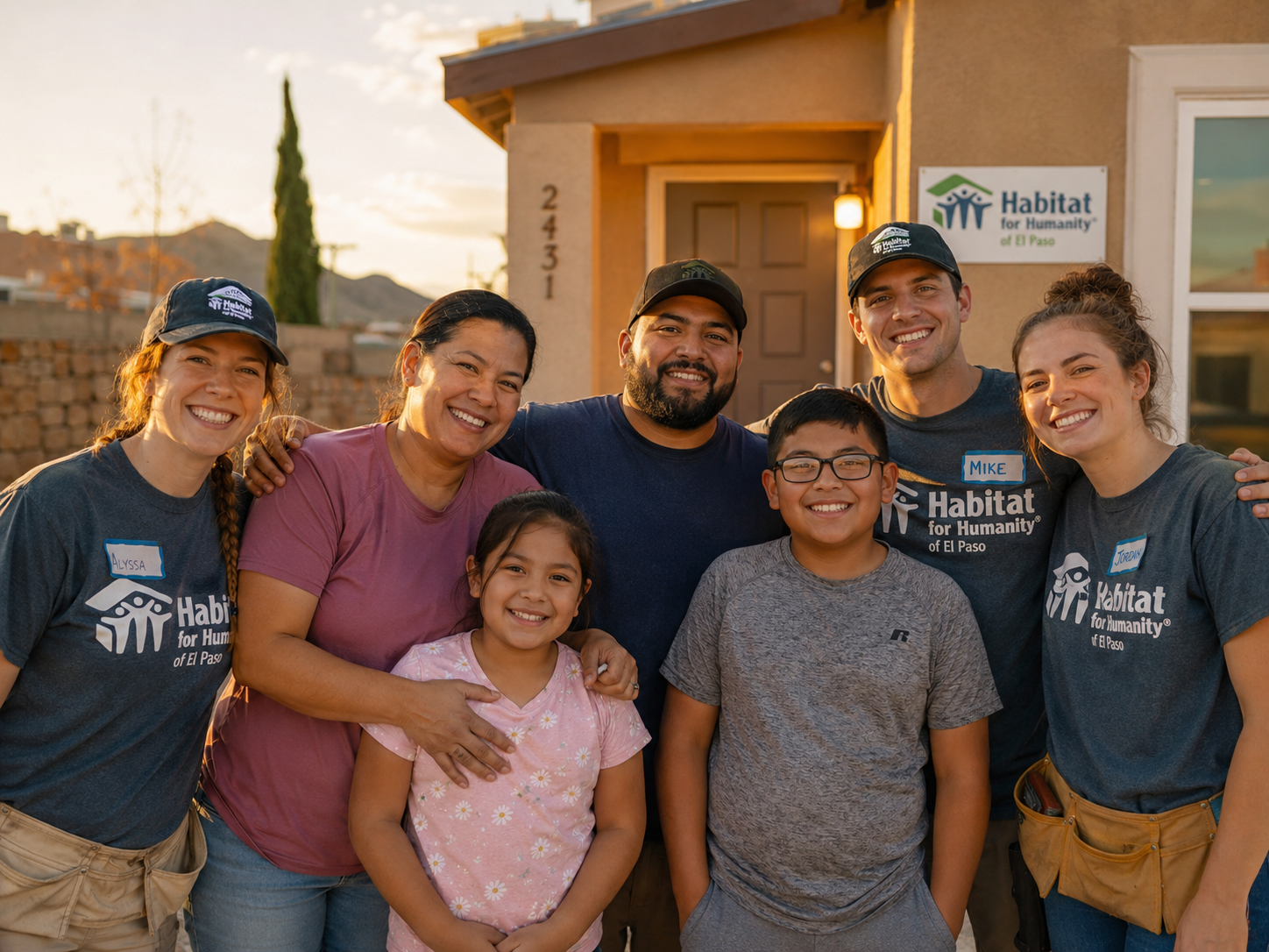 Habitat homeowner family and volunteers celebrate in front of a completed El Paso home at sunset.