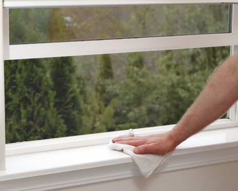 A person is cleaning a window with a cloth.